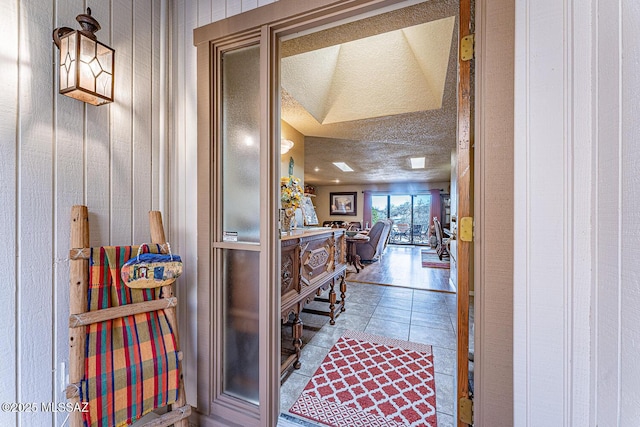 corridor featuring tile patterned floors, wooden walls, and a textured ceiling