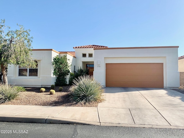 view of front facade with stucco siding, a garage, driveway, and a tiled roof