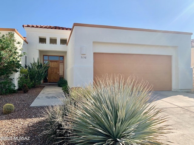 view of front of house featuring a tiled roof, an attached garage, driveway, and stucco siding