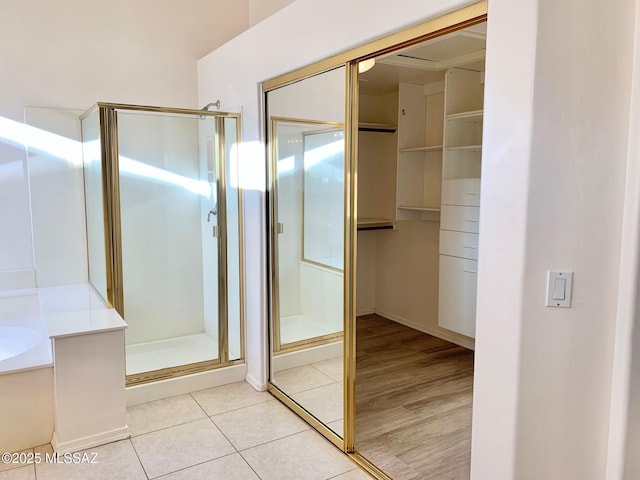 full bathroom featuring tile patterned floors, a bath, and a shower stall