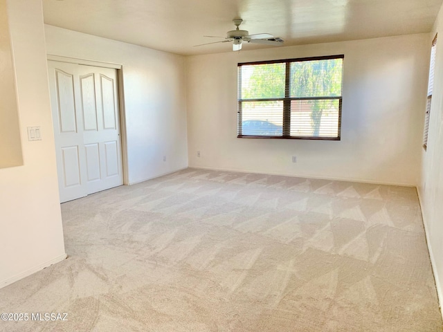 carpeted spare room with a ceiling fan