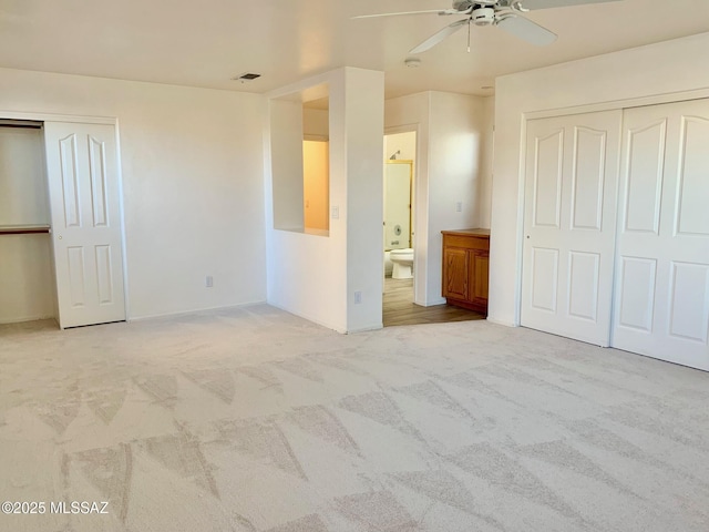 unfurnished bedroom with ensuite bath, visible vents, carpet floors, and ceiling fan