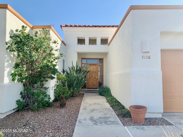 property entrance with a garage and stucco siding