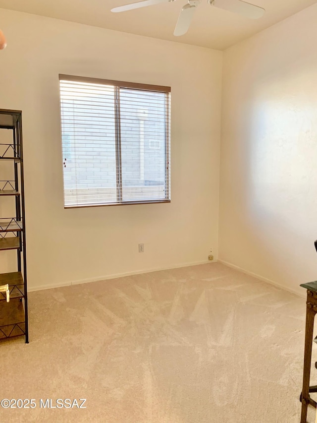 spare room with light colored carpet, baseboards, and ceiling fan