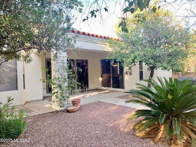 exterior space featuring a tiled roof, stucco siding, and a patio area