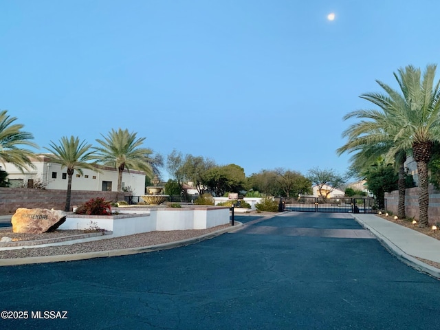 view of road with a gate, curbs, sidewalks, and a gated entry