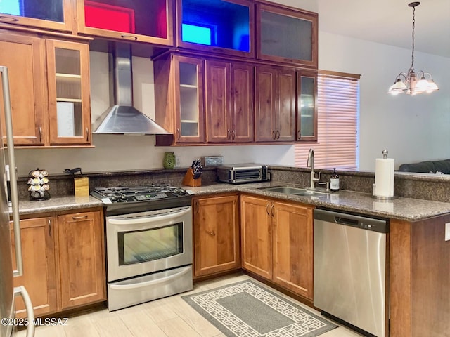 kitchen featuring a sink, a peninsula, appliances with stainless steel finishes, wall chimney exhaust hood, and a toaster