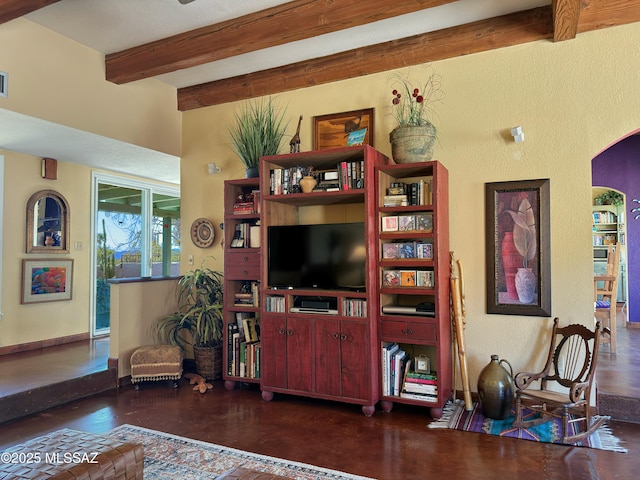 living room featuring beamed ceiling, visible vents, wood finished floors, arched walkways, and a textured wall