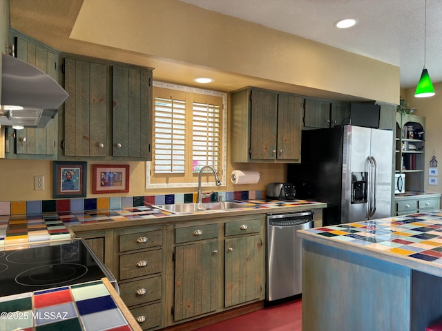 kitchen with a sink, range hood, appliances with stainless steel finishes, and tile counters