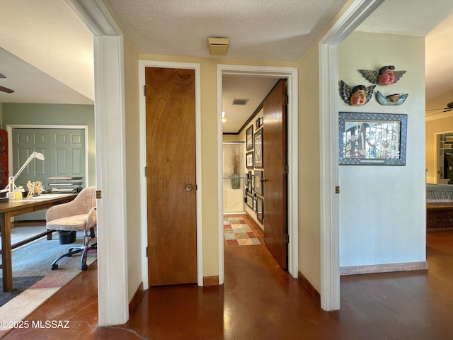 hallway featuring baseboards, visible vents, concrete floors, and a textured ceiling