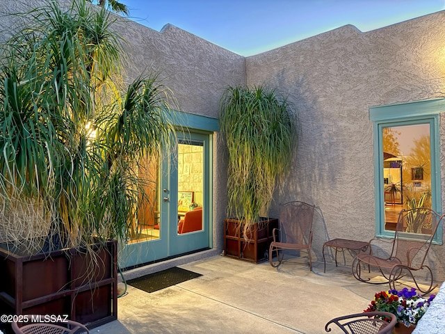 doorway to property with a patio, french doors, and stucco siding