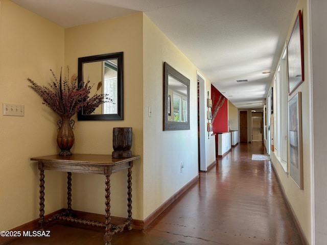 hall with visible vents, baseboards, and wood finished floors