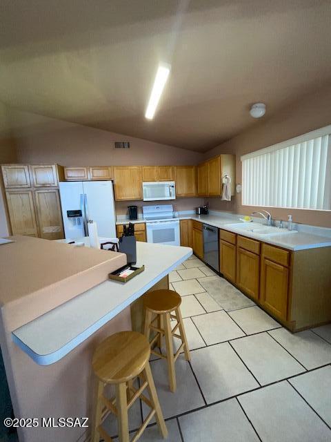 kitchen featuring white appliances, light countertops, lofted ceiling, and a sink