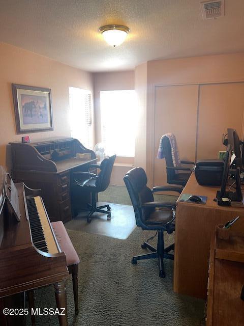 carpeted home office with visible vents and a textured ceiling