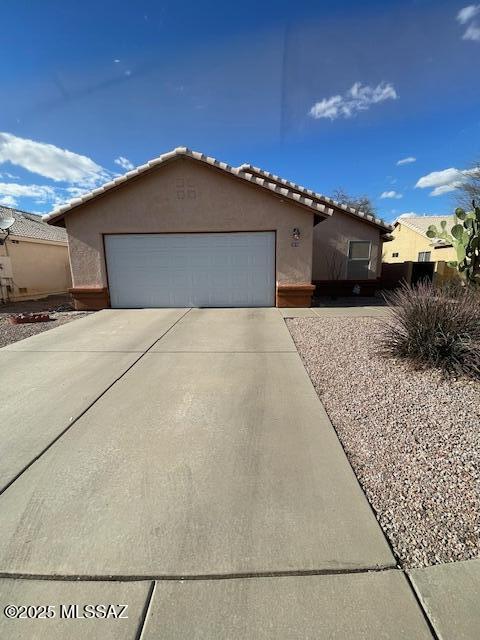 view of front of home with stucco siding, driveway, and a tile roof