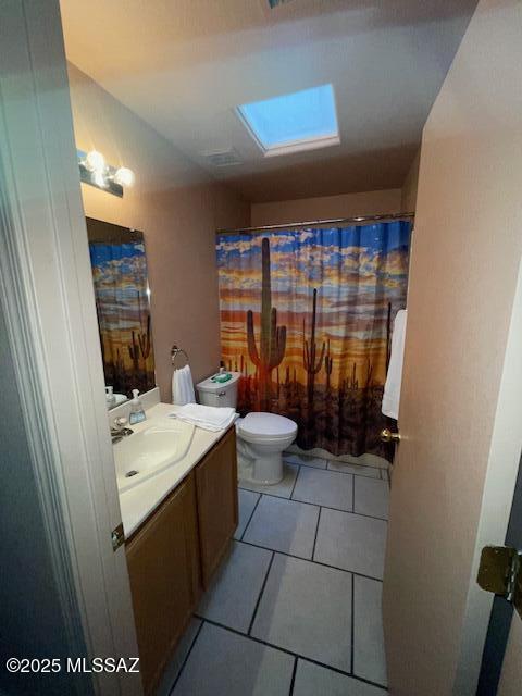 full bathroom featuring tile patterned floors, toilet, a skylight, and vanity