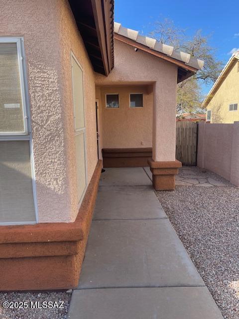 view of side of property featuring stucco siding and fence