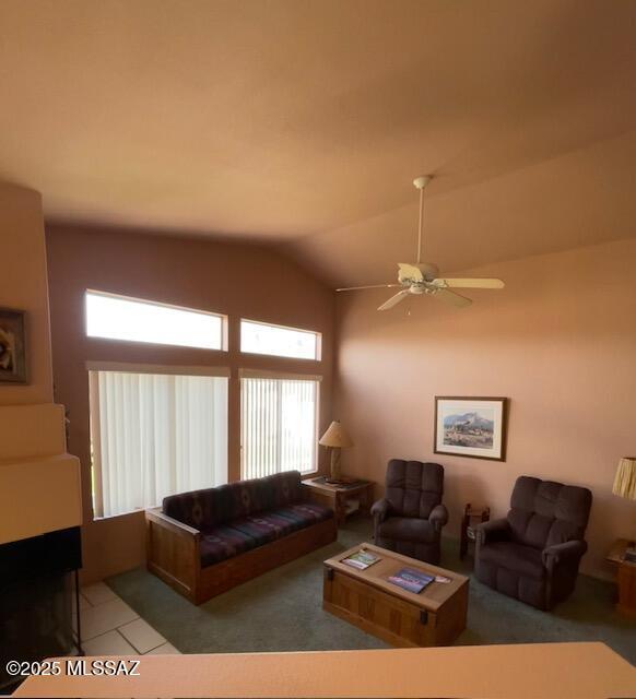 tiled living area with a ceiling fan and vaulted ceiling