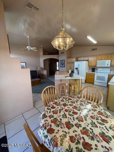 dining space featuring arched walkways, visible vents, ceiling fan with notable chandelier, and light tile patterned floors