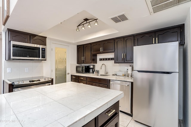 1200 E River Rd Unit J127, Tucson, AZ 85718 - kitchen with stainless steel appliances, a raised ceiling, a sink, dark brown cabinets, and tile countertops