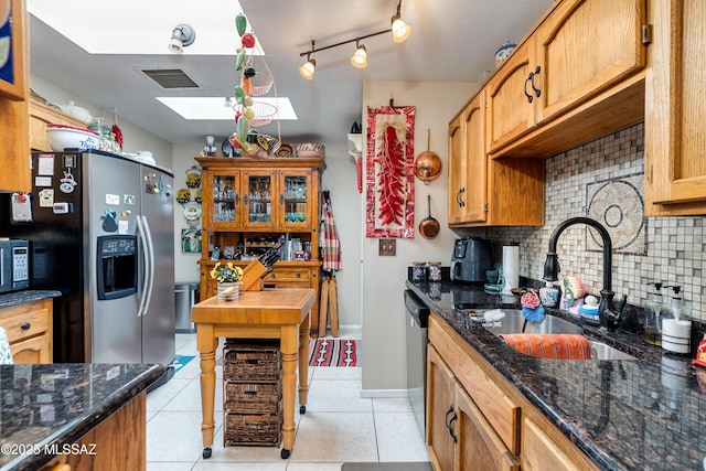 kitchen featuring visible vents, backsplash, light tile patterned floors, stainless steel appliances, and a sink