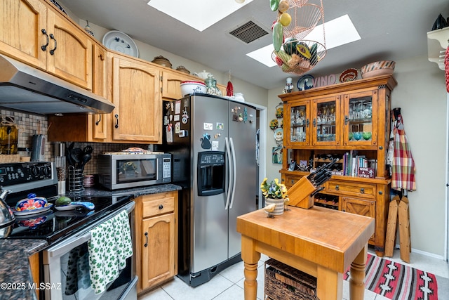 kitchen with visible vents, a skylight, under cabinet range hood, appliances with stainless steel finishes, and dark countertops