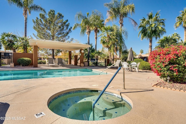 pool featuring fence, a hot tub, and a patio area