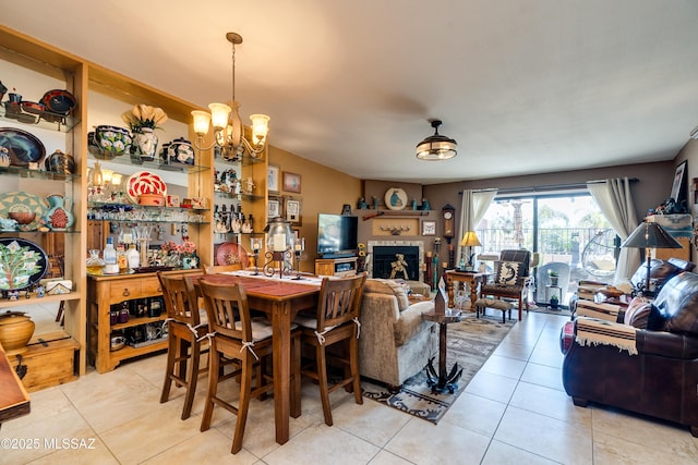 dining room featuring light tile patterned floors, a notable chandelier, and a tiled fireplace