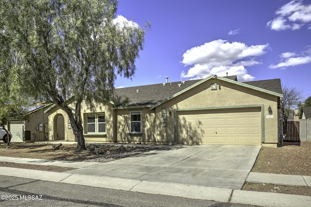 single story home with concrete driveway, an attached garage, fence, and stucco siding