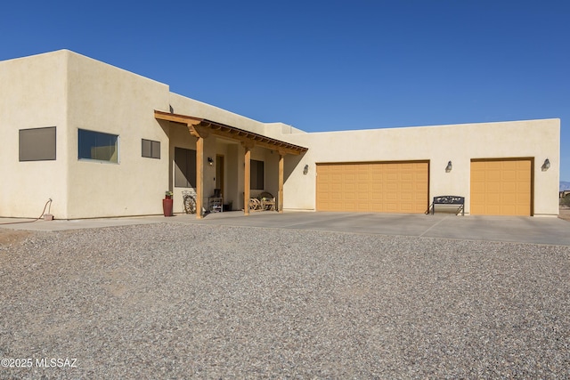 pueblo revival-style home with stucco siding and concrete driveway