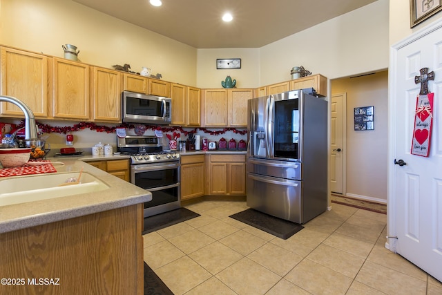 kitchen featuring light brown cabinets, a sink, appliances with stainless steel finishes, light countertops, and light tile patterned floors