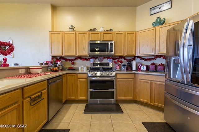 kitchen with light tile patterned floors, stainless steel appliances, light countertops, and a sink