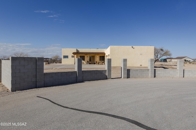 pueblo-style home with stucco siding and fence