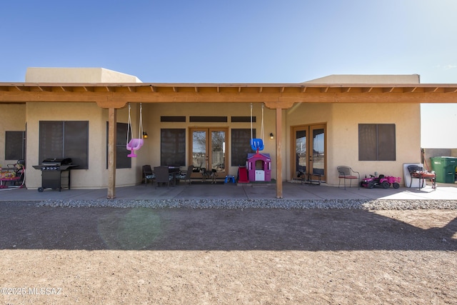 rear view of property featuring a patio, french doors, and stucco siding