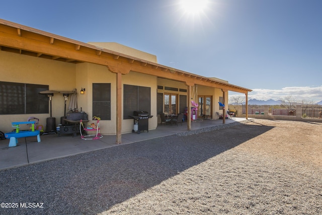 back of house featuring a patio area, fence, and stucco siding