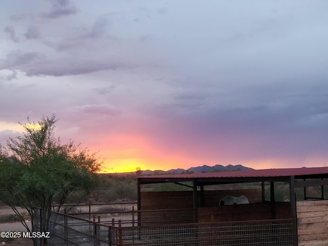 property exterior at dusk with a mountain view and an exterior structure