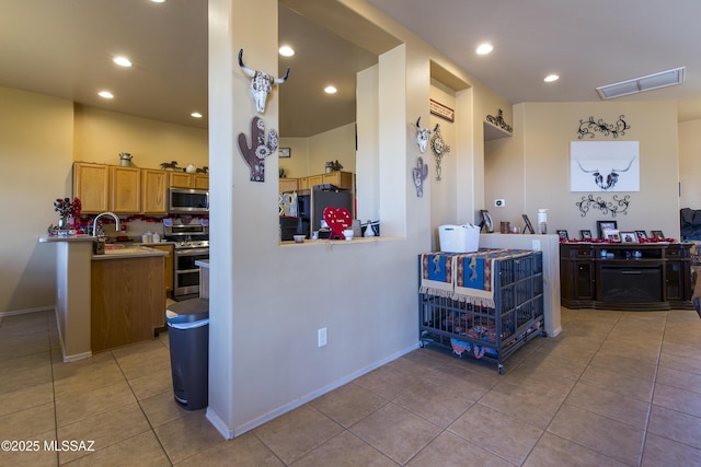 kitchen featuring visible vents, stainless steel appliances, brown cabinetry, light countertops, and light tile patterned floors