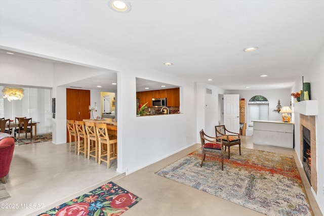 living room with recessed lighting, baseboards, concrete flooring, and a lit fireplace