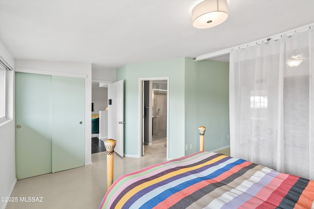 bedroom with baseboards, concrete flooring, and connected bathroom