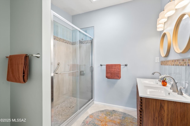 full bathroom featuring baseboards, double vanity, a stall shower, a sink, and tile patterned floors