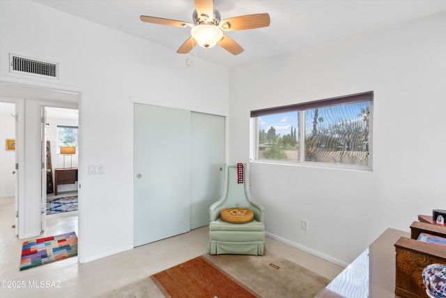 living area with a wealth of natural light, visible vents, carpet, and a ceiling fan