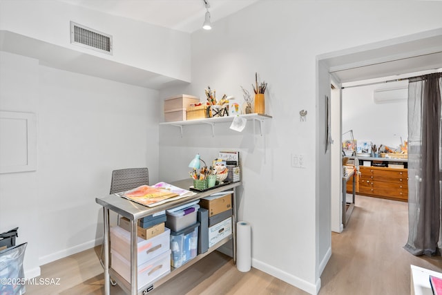 interior space with light wood finished floors, visible vents, track lighting, and baseboards