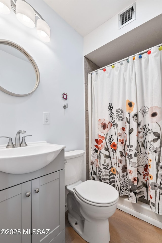 bathroom with visible vents, toilet, vanity, and wood finished floors