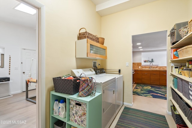 laundry room featuring washer and dryer, baseboards, and a sink