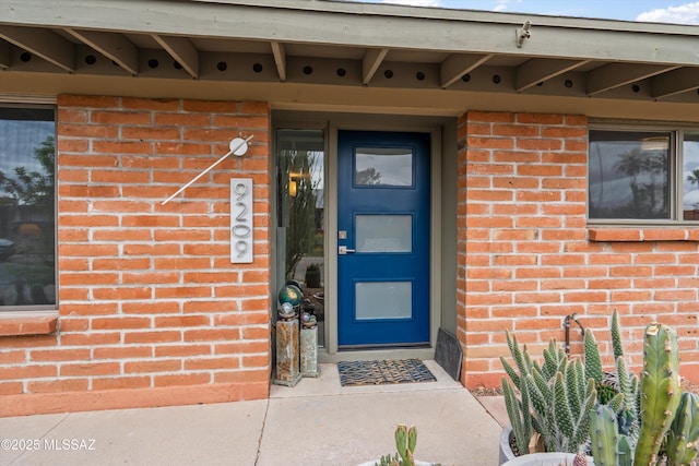 view of exterior entry featuring brick siding
