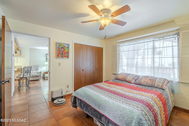 bedroom featuring a ceiling fan, light tile patterned flooring, baseboards, and a closet