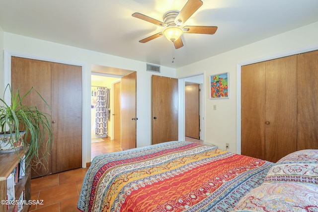 bedroom with visible vents, two closets, and ceiling fan