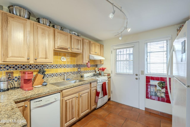 kitchen featuring white appliances, a sink, decorative backsplash, under cabinet range hood, and tile patterned floors