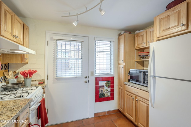 kitchen featuring white appliances, light tile patterned floors, light brown cabinets, under cabinet range hood, and backsplash