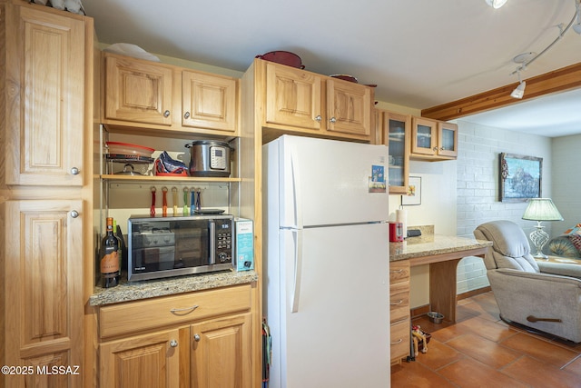 kitchen featuring stainless steel microwave, glass insert cabinets, open floor plan, freestanding refrigerator, and tile patterned floors